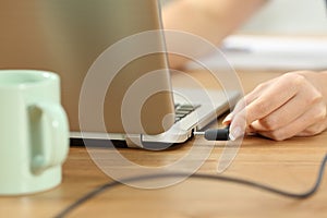 Woman plugging charger in a laptop