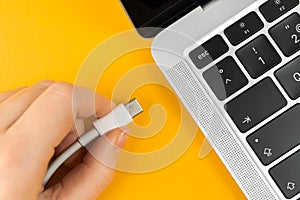 Woman plugging charger in a laptop. Type C charging port. Low battery concept photo