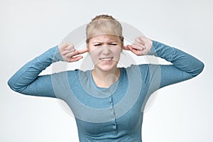 Woman with plugging ears, closing her eyes, pretending not to hear what she is told