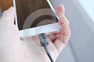 Woman plugging a USB cable into a smartphone connector to charge. Special charging connector for phone