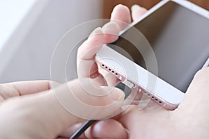 Woman plugging a USB cable into a smartphone connector to charge. Special charging connector for phone