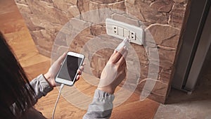 Woman plugs the phone charger into the socket