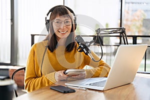 Woman podcaster in headphones and glasses looking at camera and smiling