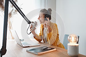 Woman podcaster talk into microphone on table