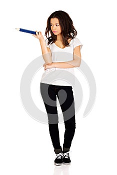 Woman pointing aside with big pencil.