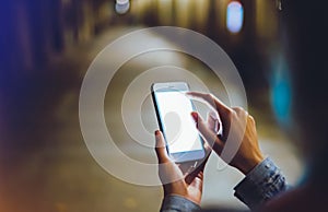 Woman pointing finger on blank screen smartphone on background bokeh light in night atmospheric city