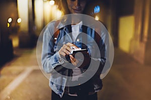 Woman pointing finger on blank screen smartphone on background bokeh light in night atmospheric city, blogger hipster