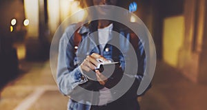 Woman pointing finger on blank screen smartphone on background bokeh light in night atmospheric city, blogger hipster using in han