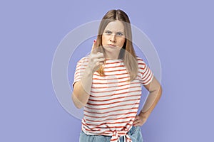 Woman pointing finger and looking with dissatisfied suspicious expression, warning about troubles.