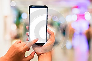 Woman pointing finger on smartphone with empty blank screen monitor on the background bokeh light in a luxury shopping store