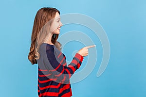 Woman pointing finger to the right with happy expression, showing copy space for advertisement.