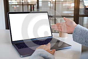 A woman pointing hand and touching on laptop touchpad with blank white desktop screen in office