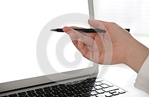 Woman pointing at modern laptop with blank screen