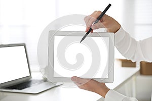 Woman pointing at modern tablet with blank screen in office