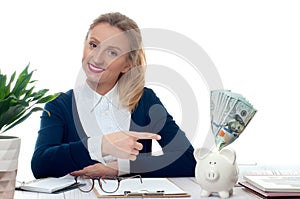 Woman pointing piggy bank with bunch of money banknotes