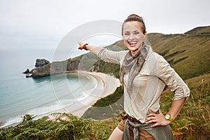 Woman pointing on something in front of ocean view landscape