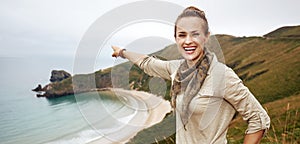 Woman pointing on something in front of ocean view landscape