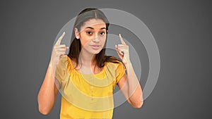 Woman pointing to her temples on grey background