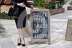 Woman points hand on the chalk stand, advertising street