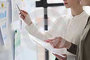 Woman points pen to researched paper sheet on whiteboard photo