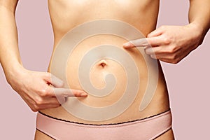 Woman points to the abdomen, circle arrows on the stomach