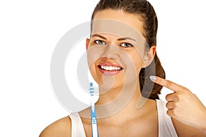 Woman poiting teeth with toothbrush over white background.