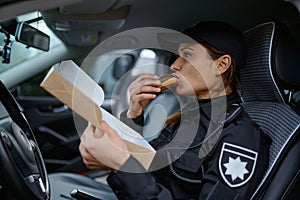 Woman police officer eating donut in car