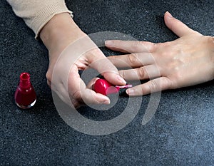 Woman polishing her nails on the gray background.