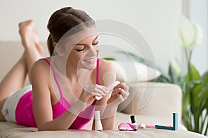 Woman polishing nails with nail buffer at home