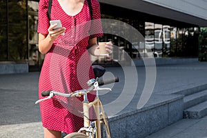 Woman in polka dot dress with bike commuting, checking mail onl