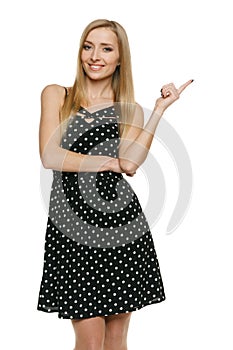 Woman in polka dot dress pointing at empty copy space