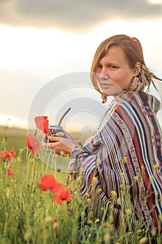 Woman in poncho with calabash on flower field