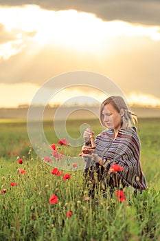 Woman in poncho with singing bowl on flower field