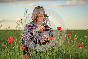 Woman in poncho with singing bowl on flower field