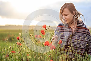 Woman in poncho sits on sunset flower field