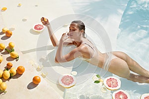 Woman In Pool. Citrus For Perfect Skin And Slim Body. Beautiful Girl In Bikini At Tropical SPA.