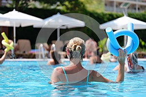 Woman in the pool doing exercises in aquafitness, back view