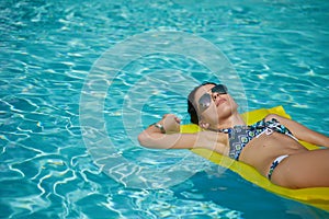 A woman in the pool floats on a blown mattress