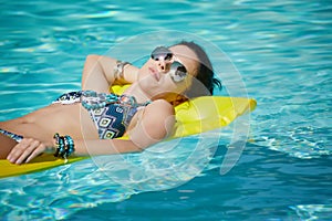 A woman in the pool floats on a blown mattress