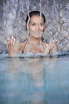 Woman in a pool under a waterfall