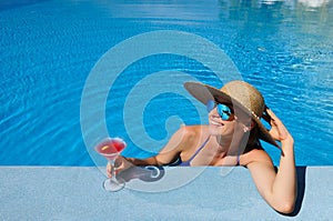 Woman at poolside with cosmopolitan cocktail