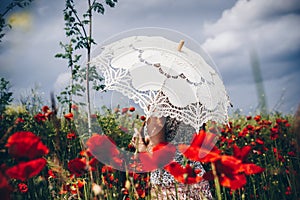 Woman in Poppy field with umbrella. Artistic interpretation