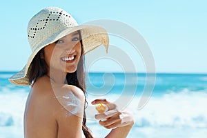 Woman, portrait and beach with sunscreen on shoulder for skin, health and happy by waves for vacation. Girl, person and