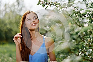 Woman portrait beautifully smiling with teeth spring happiness in nature against a green tree hand touch tenderness