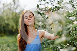 Woman portrait beautifully smiling with teeth spring happiness in nature against a green tree hand touch tenderness