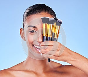 Woman, portrait and beauty, makeup and brush for foundation with cosmetics isolated on blue background, Happy Indian