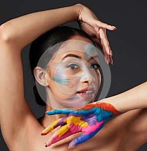 Woman, portrait and beauty with rainbow paint art on hand and face in studio with a smile. Creative skin and makeup on