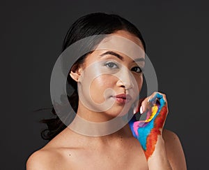 Woman, portrait and beauty with rainbow paint hand and skincare for serious face in studio. Creative skin and makeup on