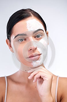 Woman, portrait and clay mask in studio, cleaning and half skincare to exfoliate on white background. Female person photo