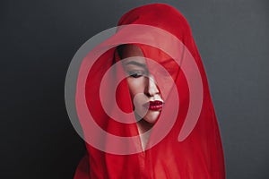 Woman portrait cover with red veil studio shot